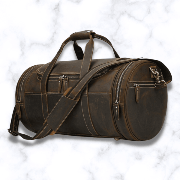 sac de voyager cuir marron vintage sur fond marbre blanc